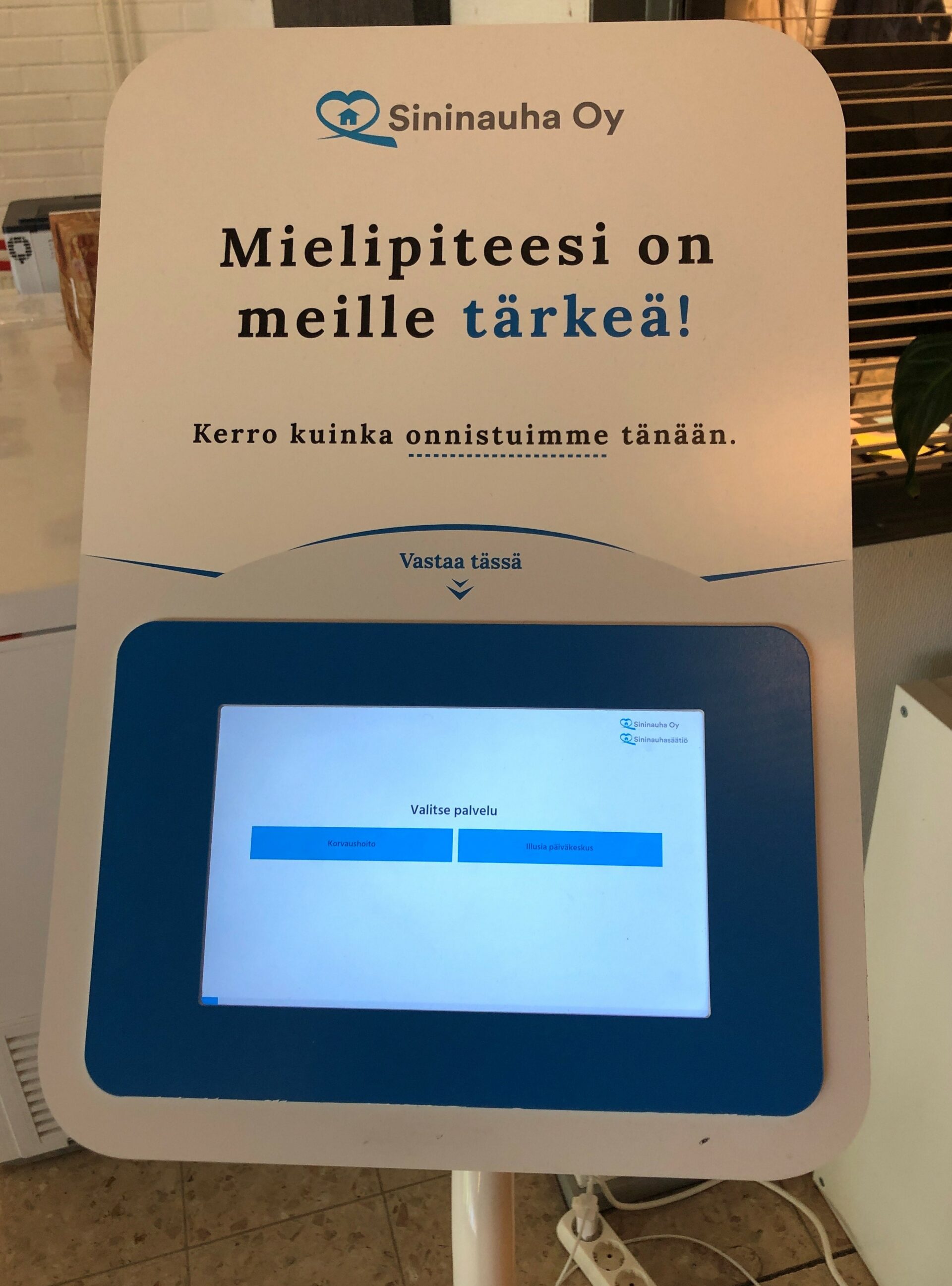 Sähköinen mielipiteenkyselykone, jonka yläpuolella on teksti Mielipiteesi on meille tärkeä.