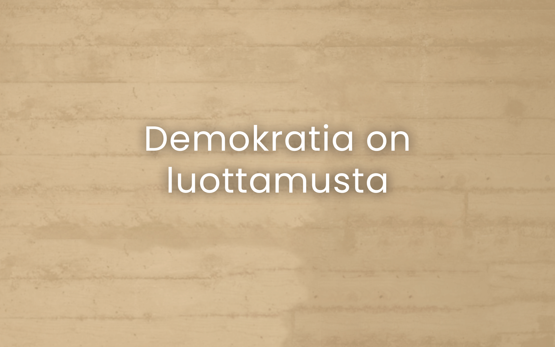Beigen värinen maalattu tiiliseinä, jonka päällä lukee Demokratia on luottamusta.